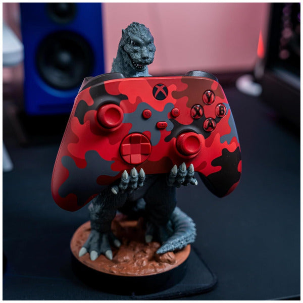 Gaming controller with red and black camouflage design featuring a Godzilla figure on top.