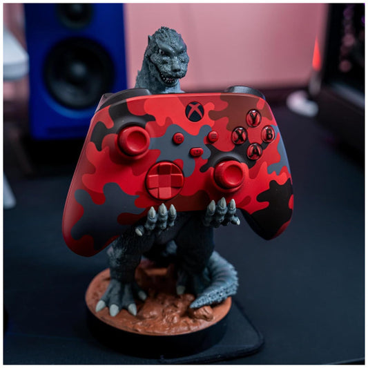 Gaming controller with red and black camouflage design featuring a Godzilla figure on top.
