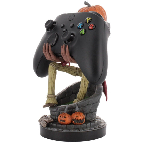 Black gaming controller shaped like a jack-o'-lantern with pumpkins on a white background